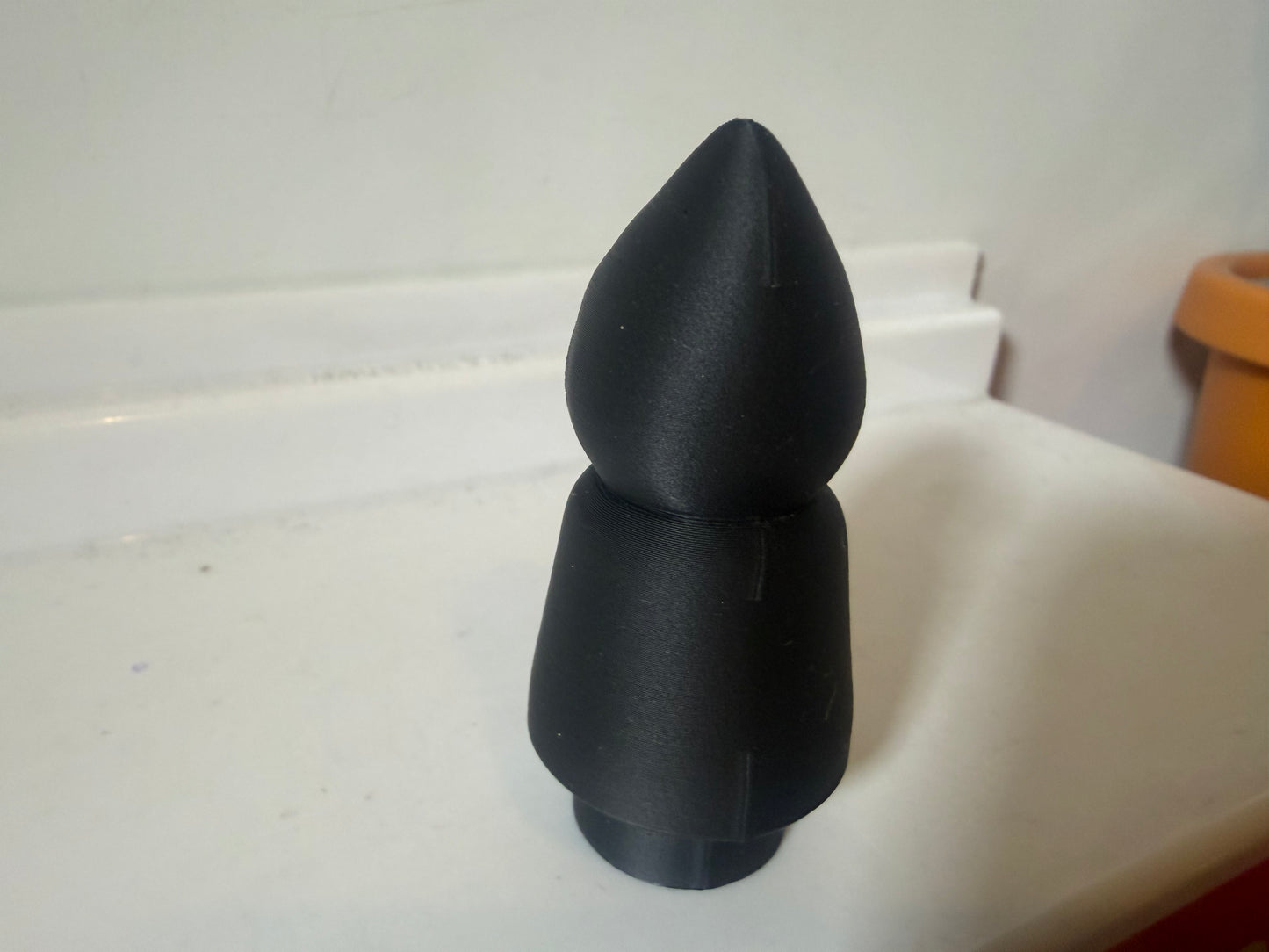 Hooded villain figure in black, plain back view with pointed hood