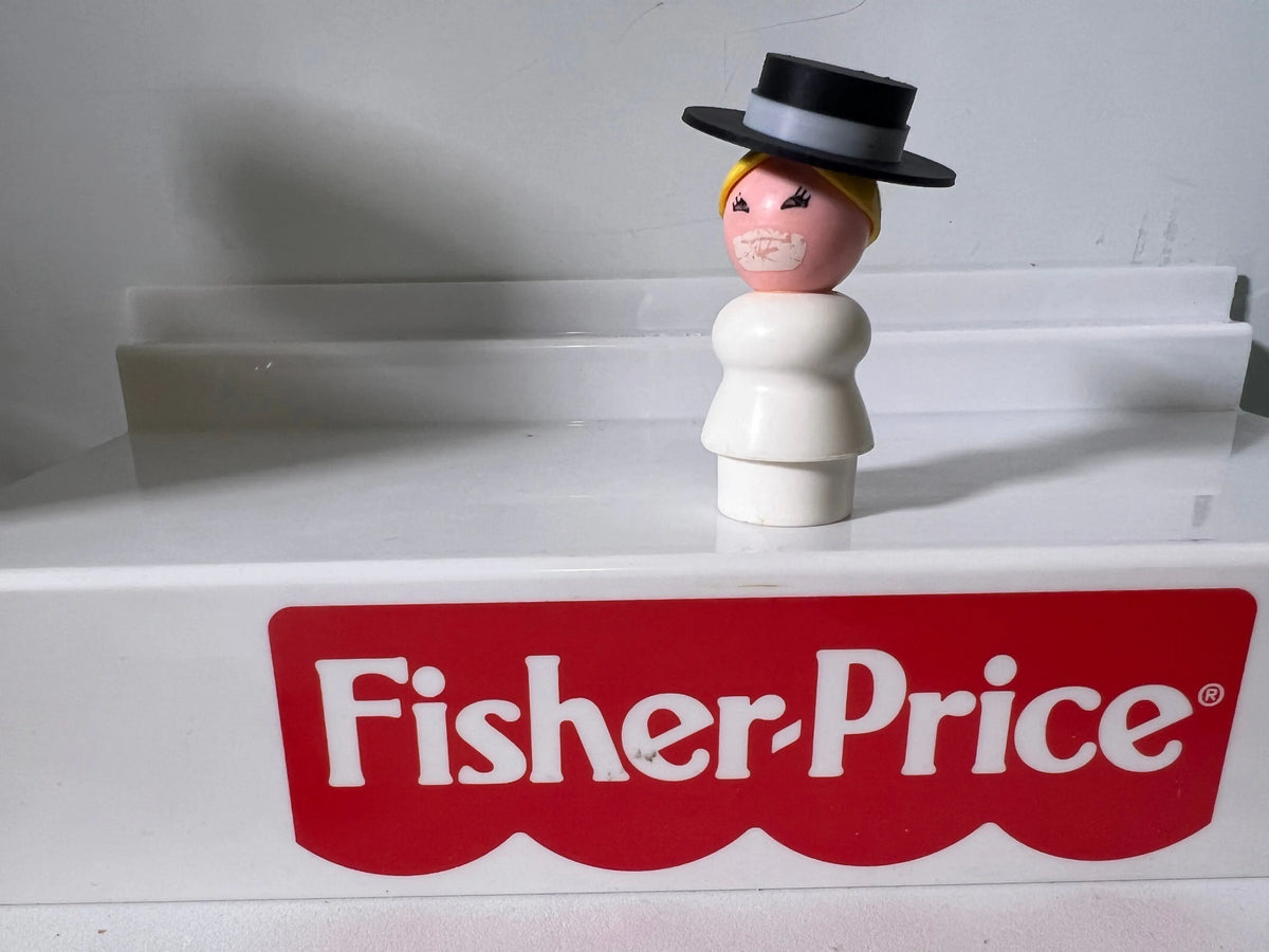 Front view vintage figure wearing black top hat and yellow hair, Fisher-Price label below