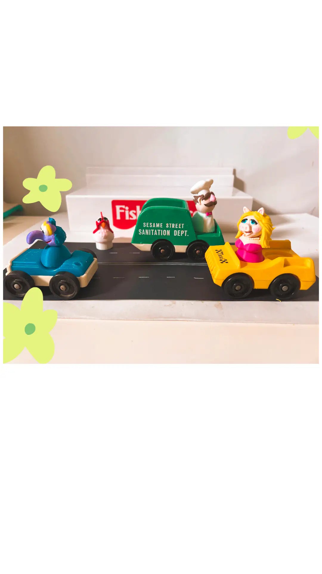 Muppets Camilla pink hen toy figure near playset vehicles.