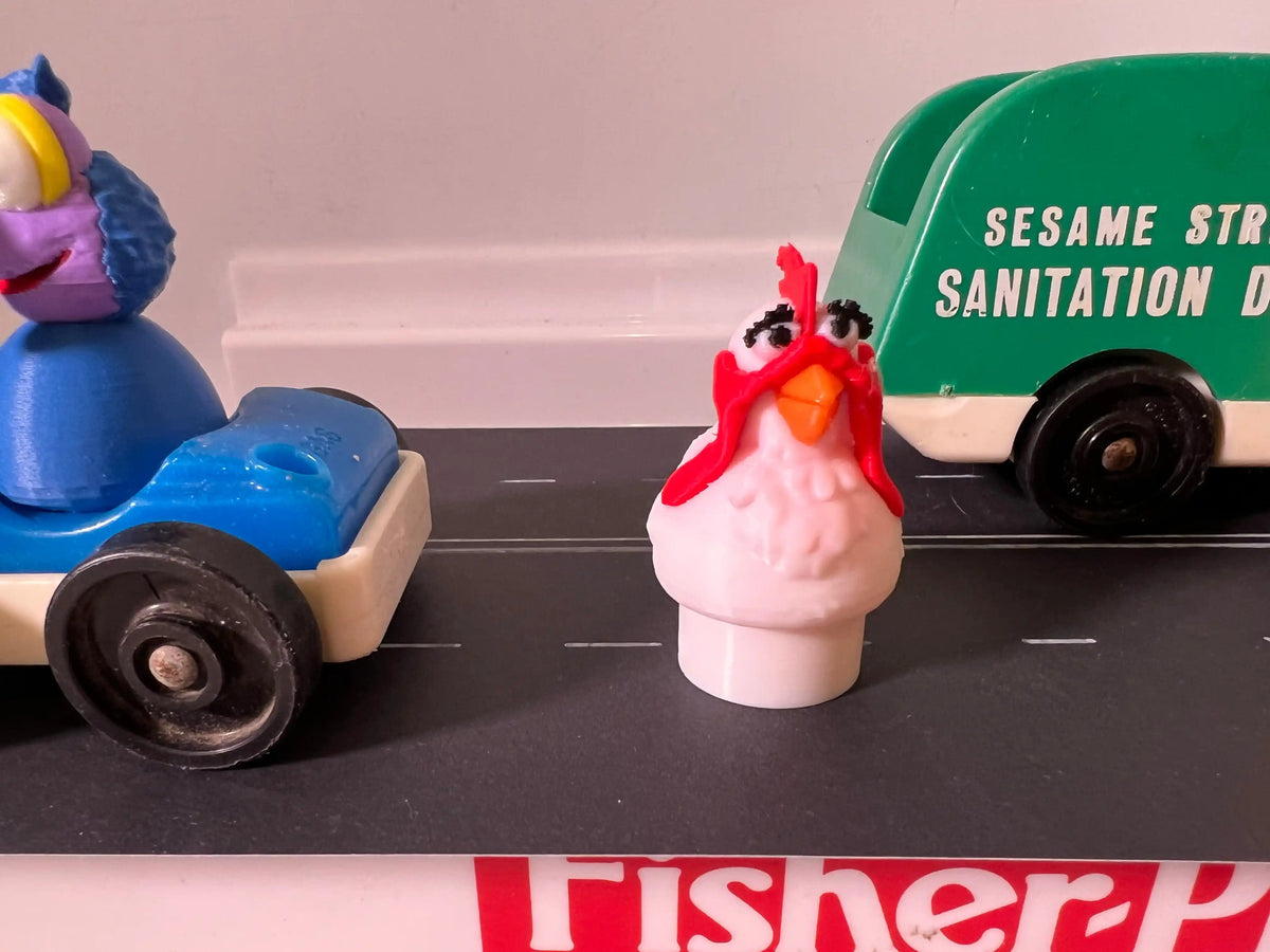 Pink hen toy figure with red comb, orange beak, and red accents.