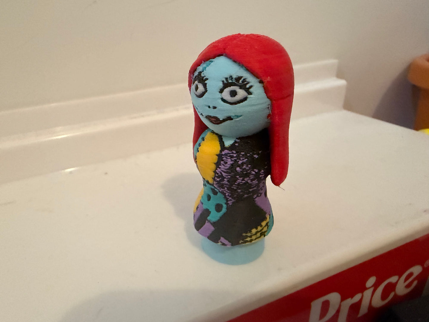 Sally figurine in red hood and blue face, colorful purple and yellow outfit