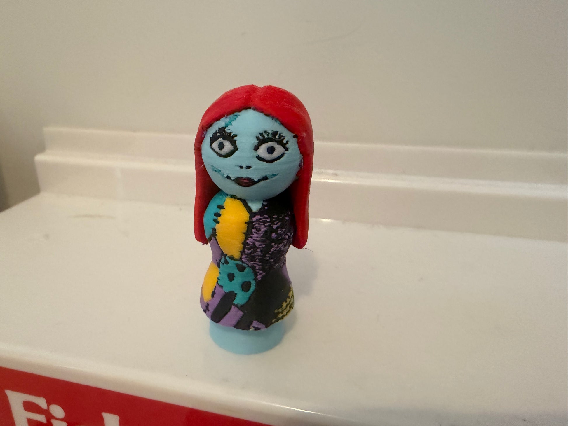 Sally collectible figure with red hood and blue face, purple patterned dress