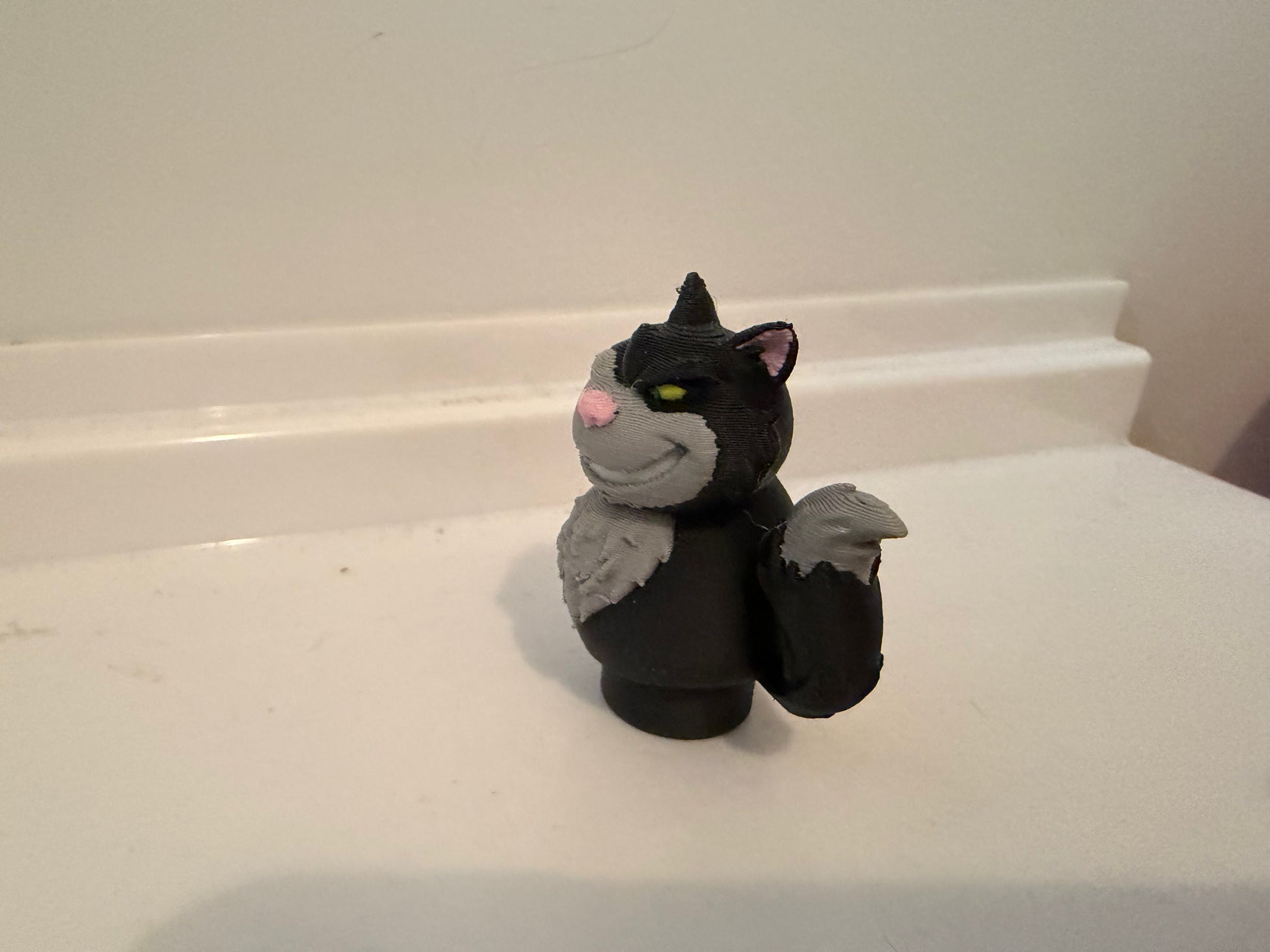 Lucifer black cat villain figure seated with pink nose and yellow-green eyes