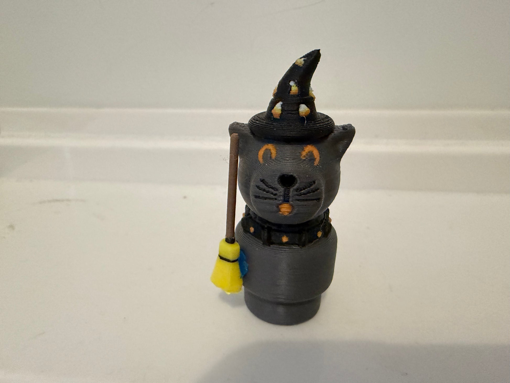 Halloween sorcerer cat figure with black witch hat, gray face, and hanging wand/staff