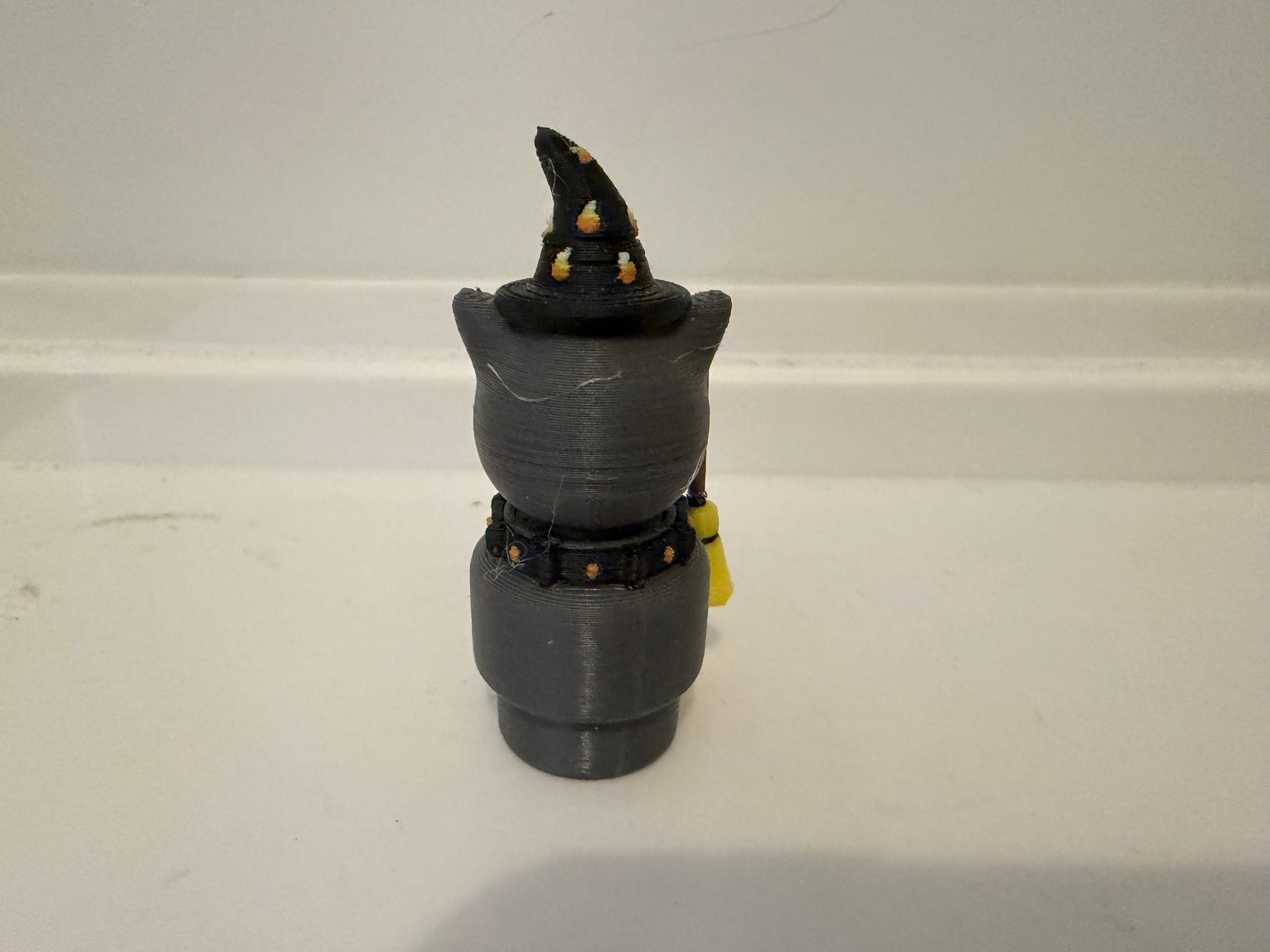 Halloween sorcerer cat figure from side view with black witch hat and gray stacked outfit