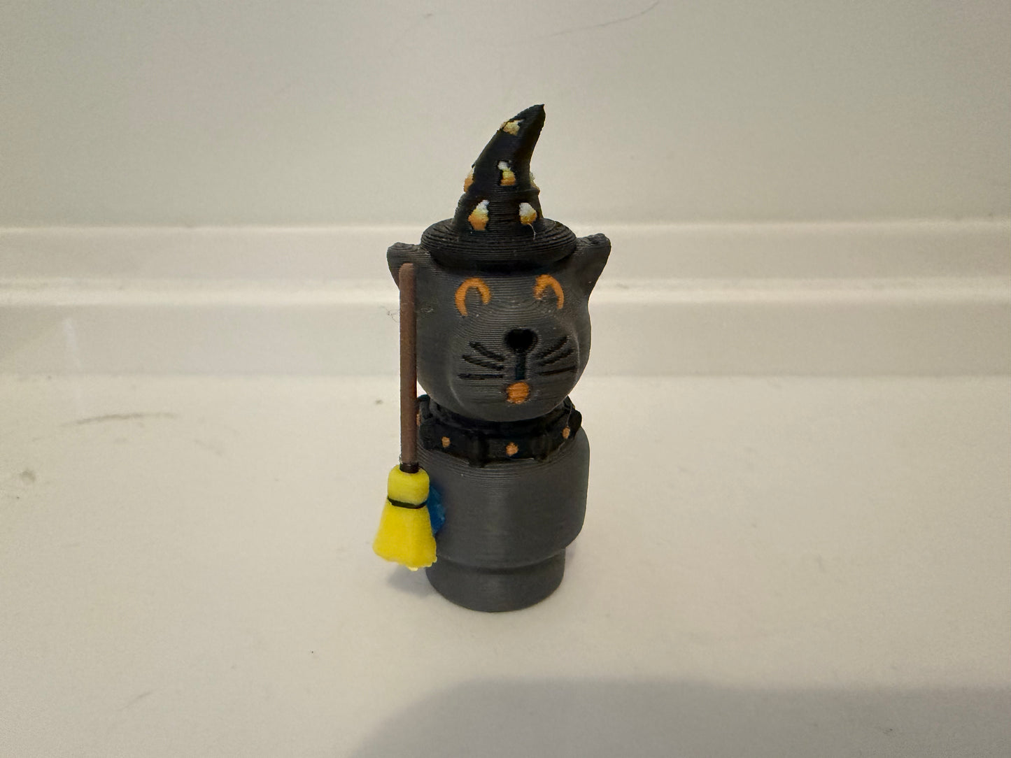 Halloween sorcerer cat figure with black witch hat, gray body, and small broom accessory