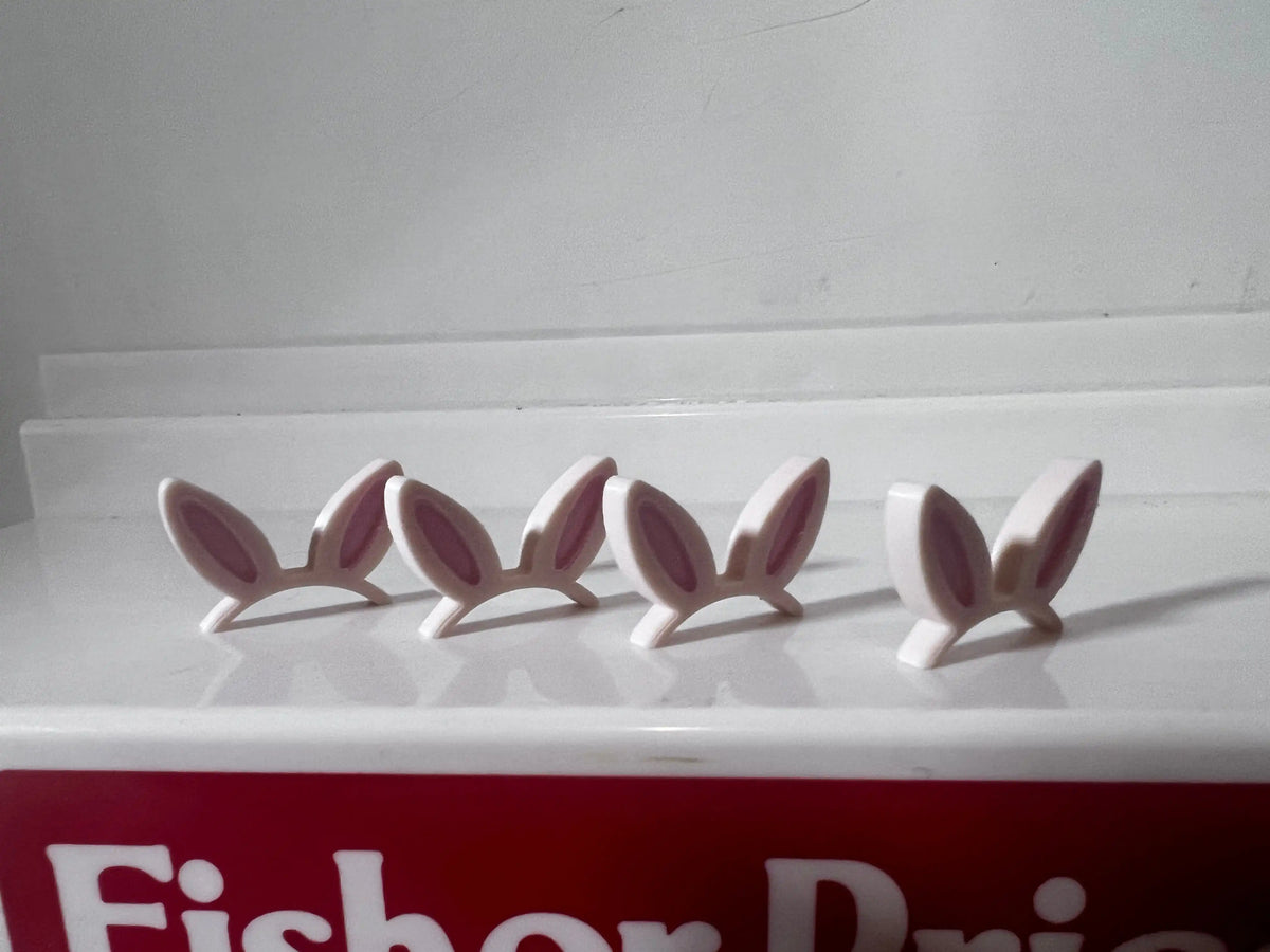 White bunny ear pieces with pink inner details, arranged in a row on a tray