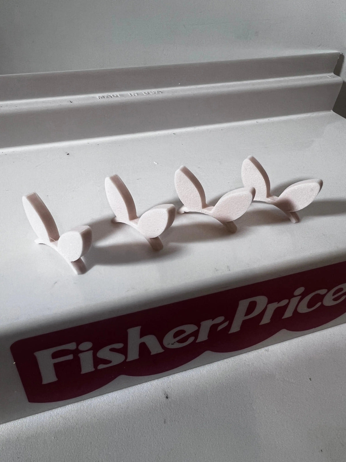 White bunny ears headband pieces with pink inner ears on a Fisher-Price box top