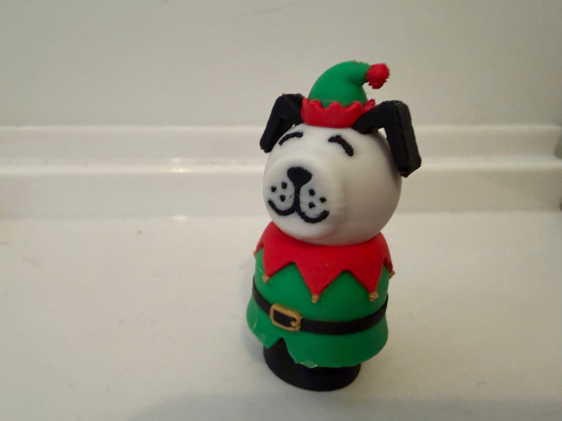 Standing dog holiday figurine wearing red top and green dress with belt