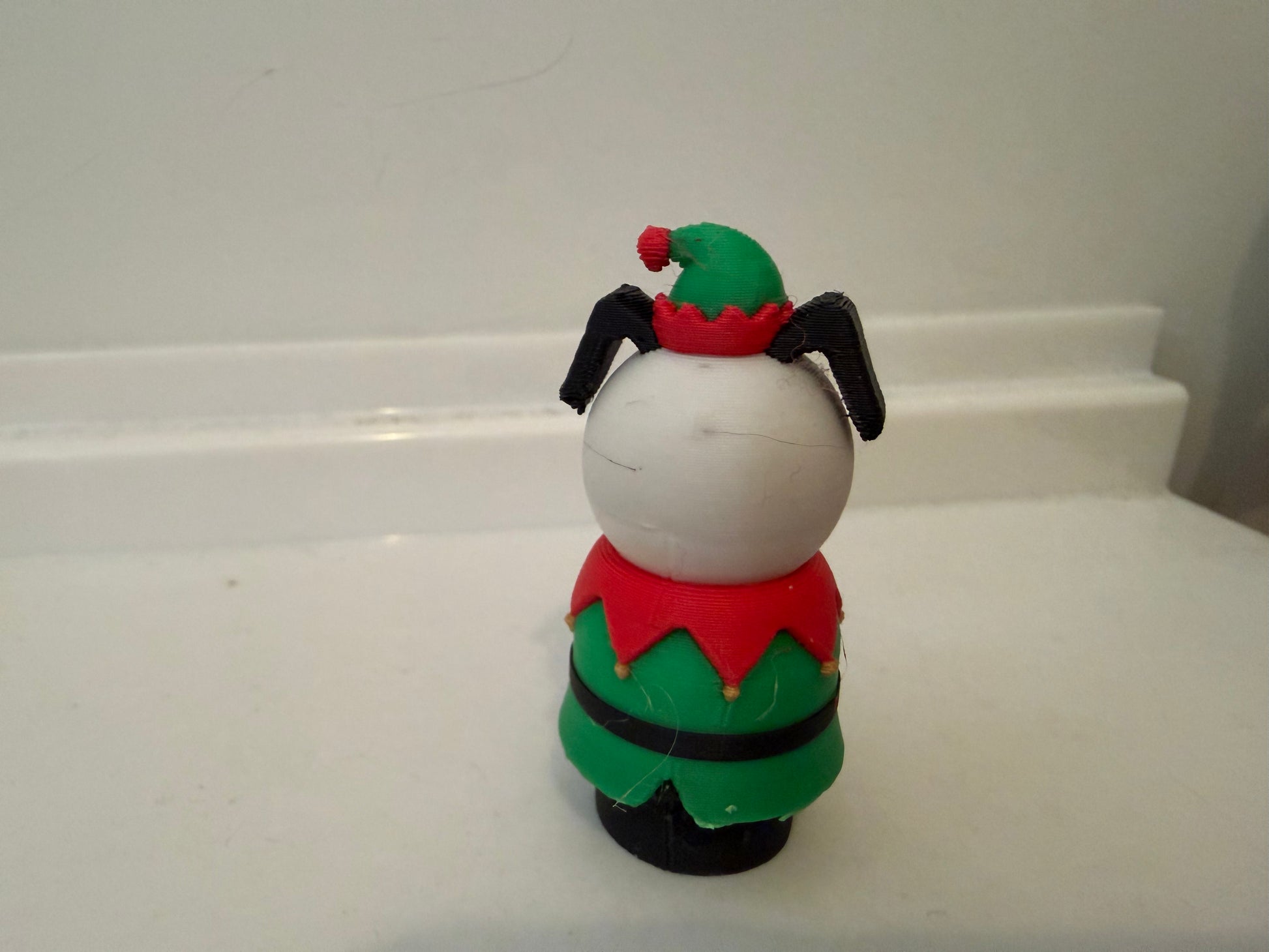 Rear view of holiday dog figurine with green outfit and red collar