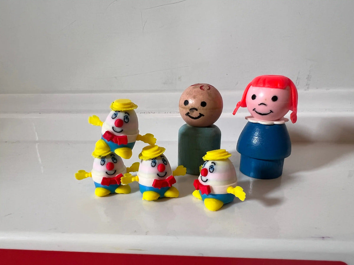 A group of custom vintage Fisher-Price Humpty Dumpty miniatures and two Little People figures on a white surface.