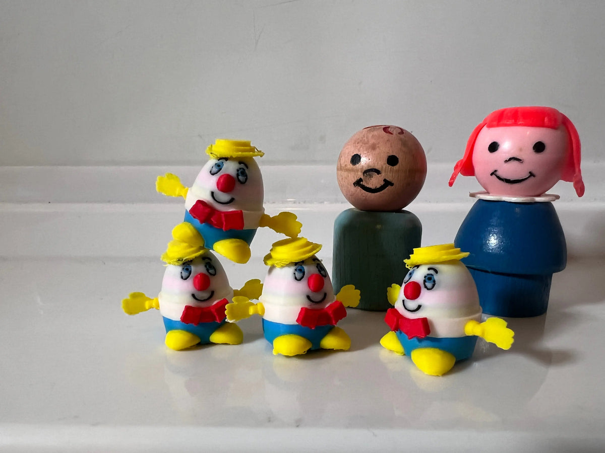 Miniature Humpty Dumpty character figurines with egg heads, yellow hats, blue outfits.