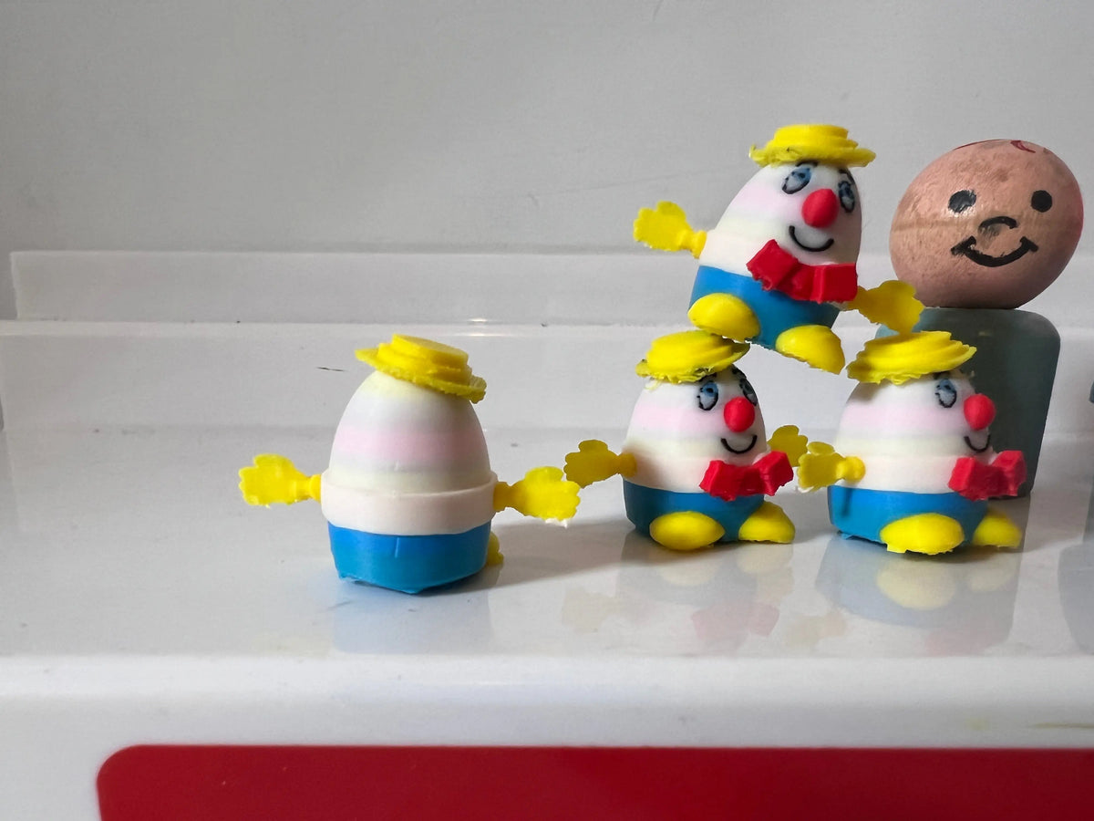 Miniature character figurines: egg-shaped heads, yellow hats, blue overalls, smiling faces.