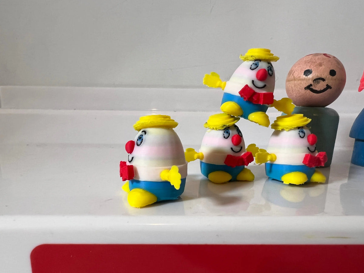 Miniature figurine group with egg heads, yellow hats, blue overalls, red noses and smiles.