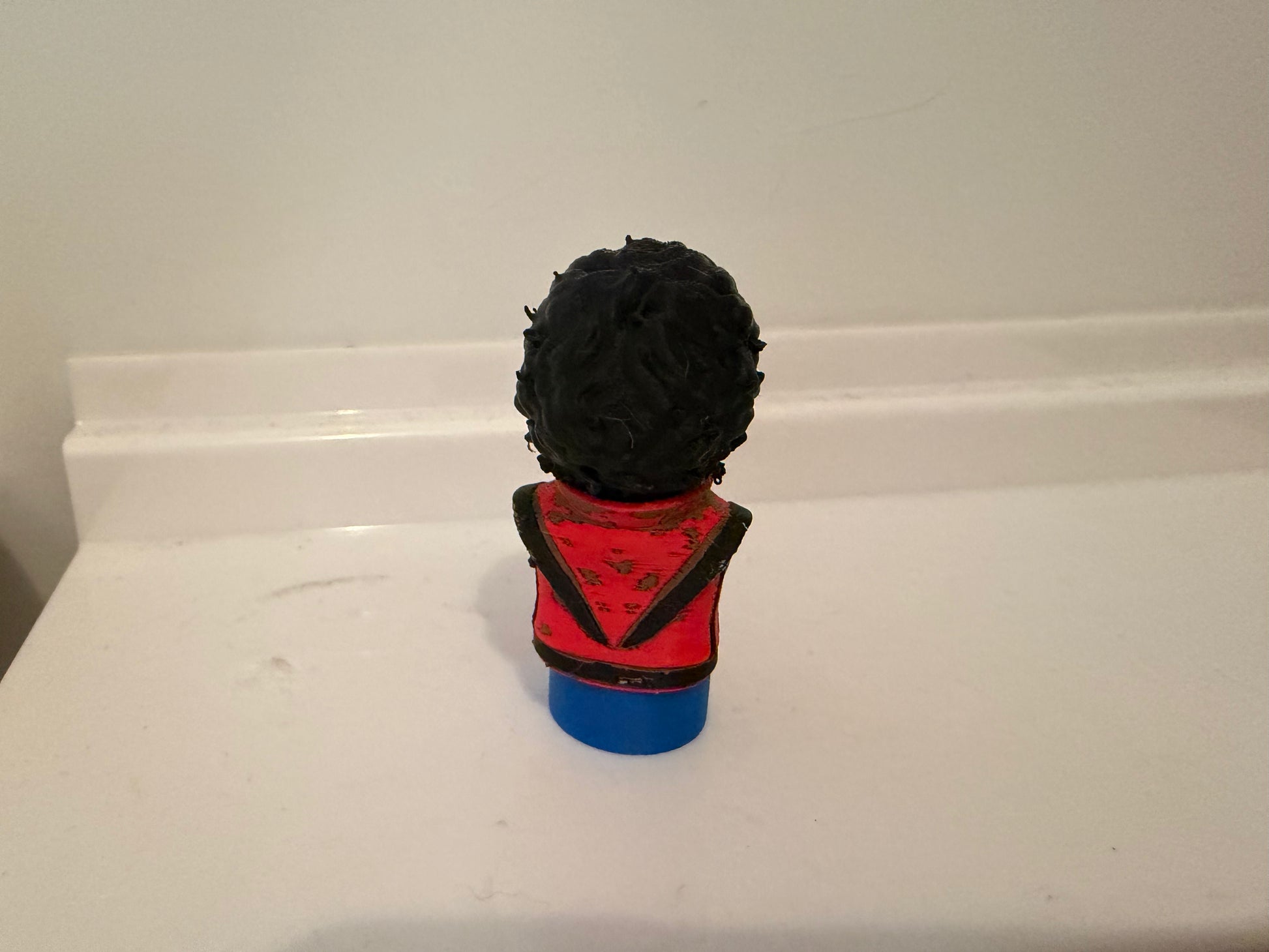 Zombie bust figurine from back, black hair, red collar, blue base