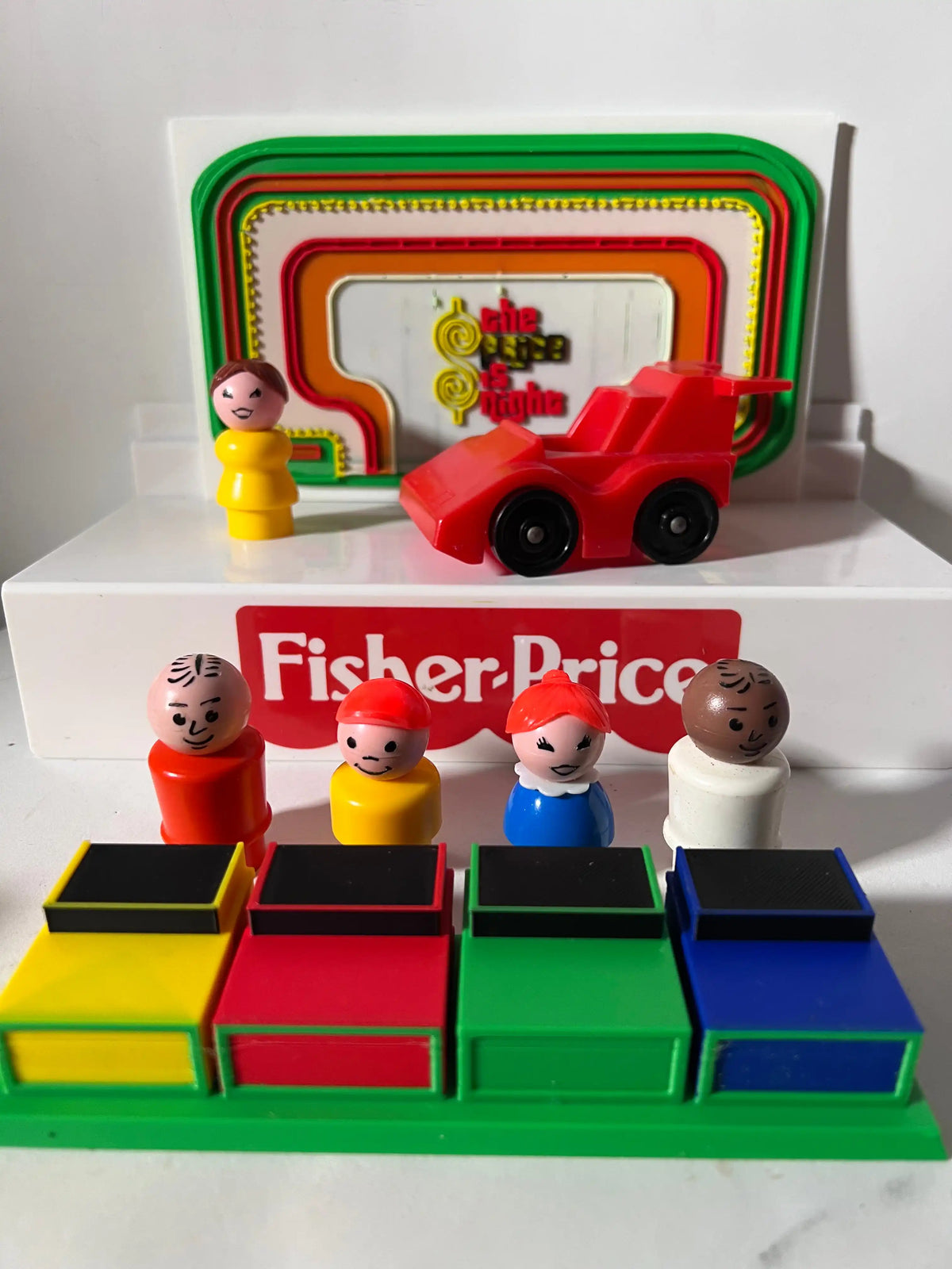 A custom 3D printed "Price Is Right" backdrop and Contestants Row with four colorful Fisher-Price Little People figures.