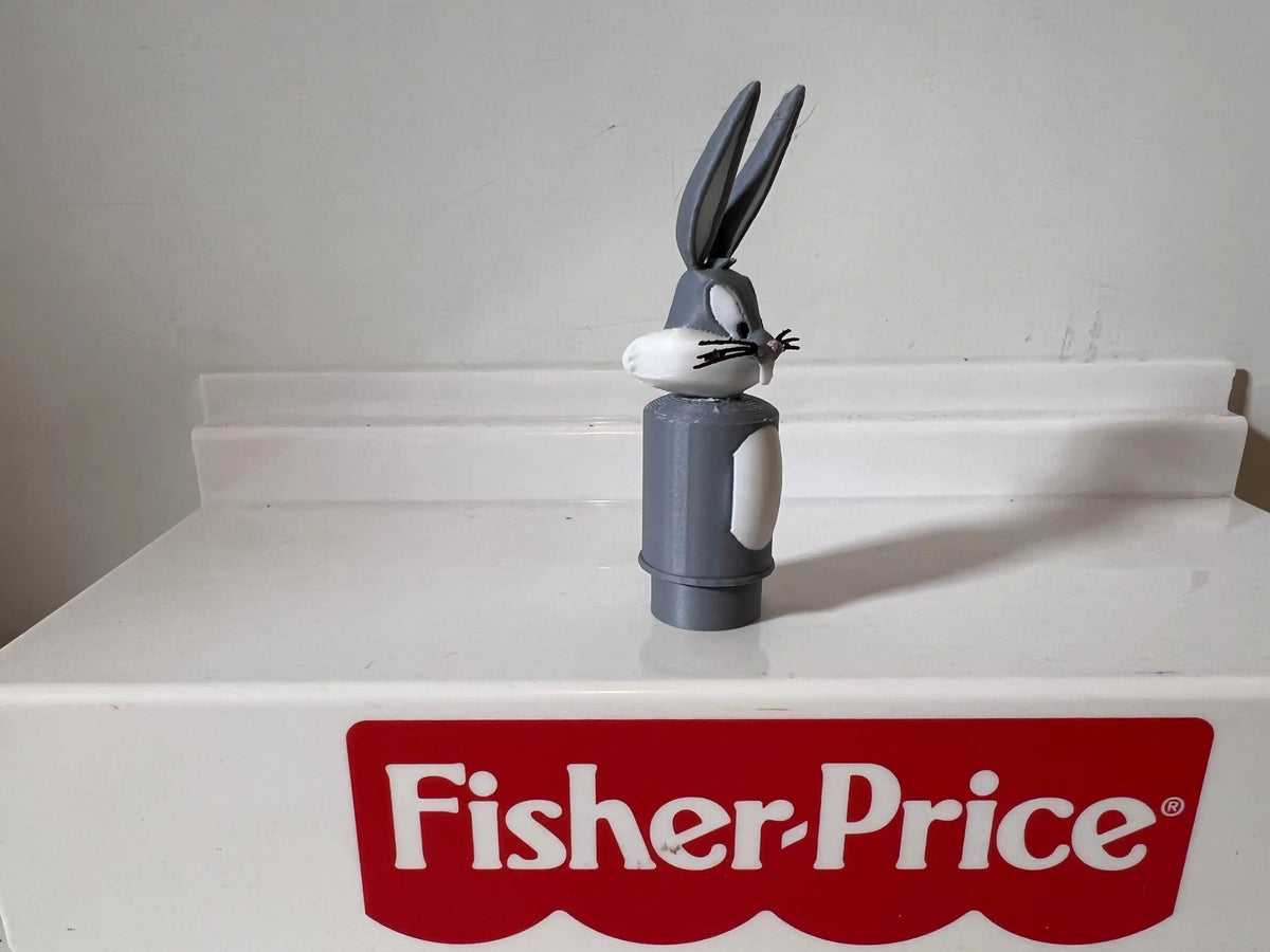 Bugs Bunny figurine wearing black ears, standing on a white Fisher-Price box