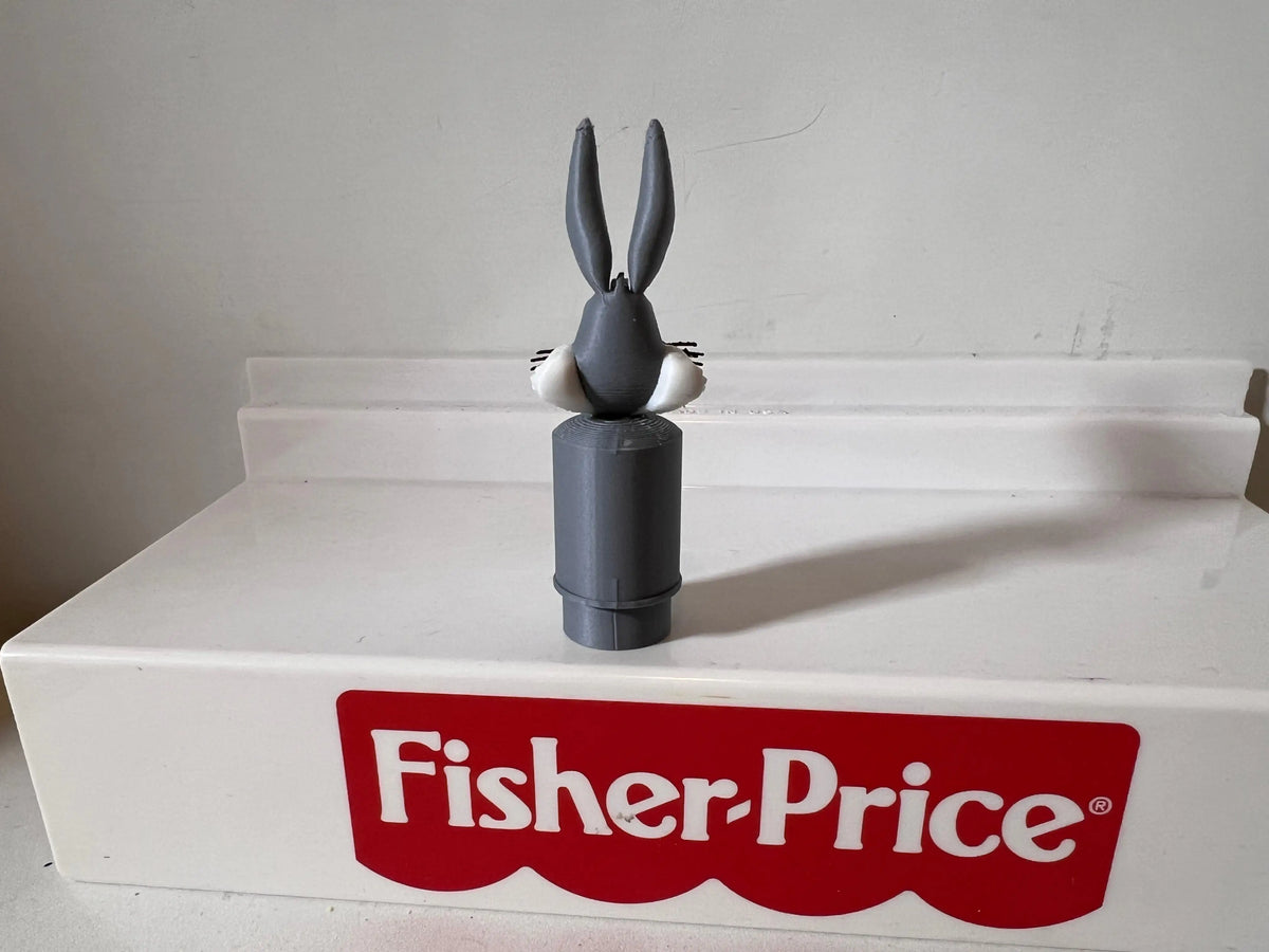 Bugs Bunny head and torso figurine on a black pedestal atop a Fisher-Price box