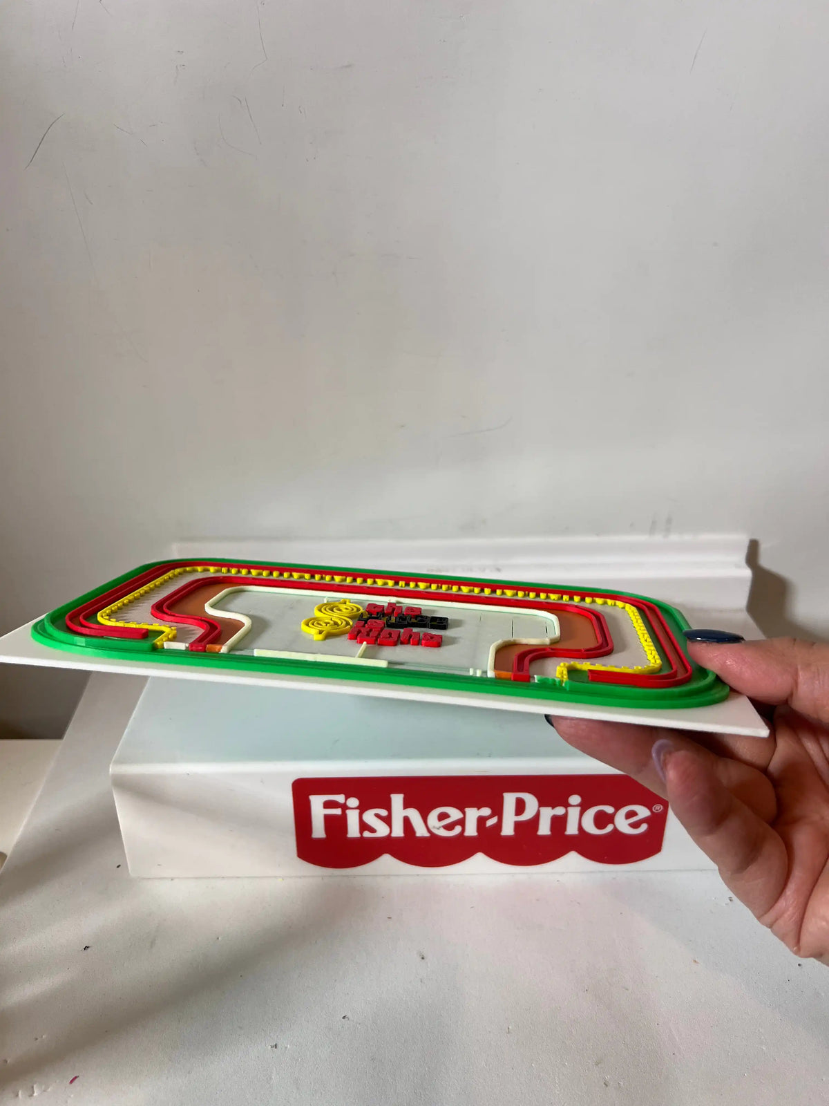 Game show backdrop panel with green border and Fisher-Price strip, held from side