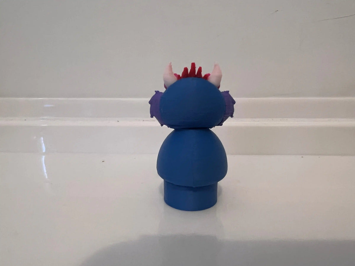 Blue monster figurine with pink spiky crest, purple head, and teal side detail