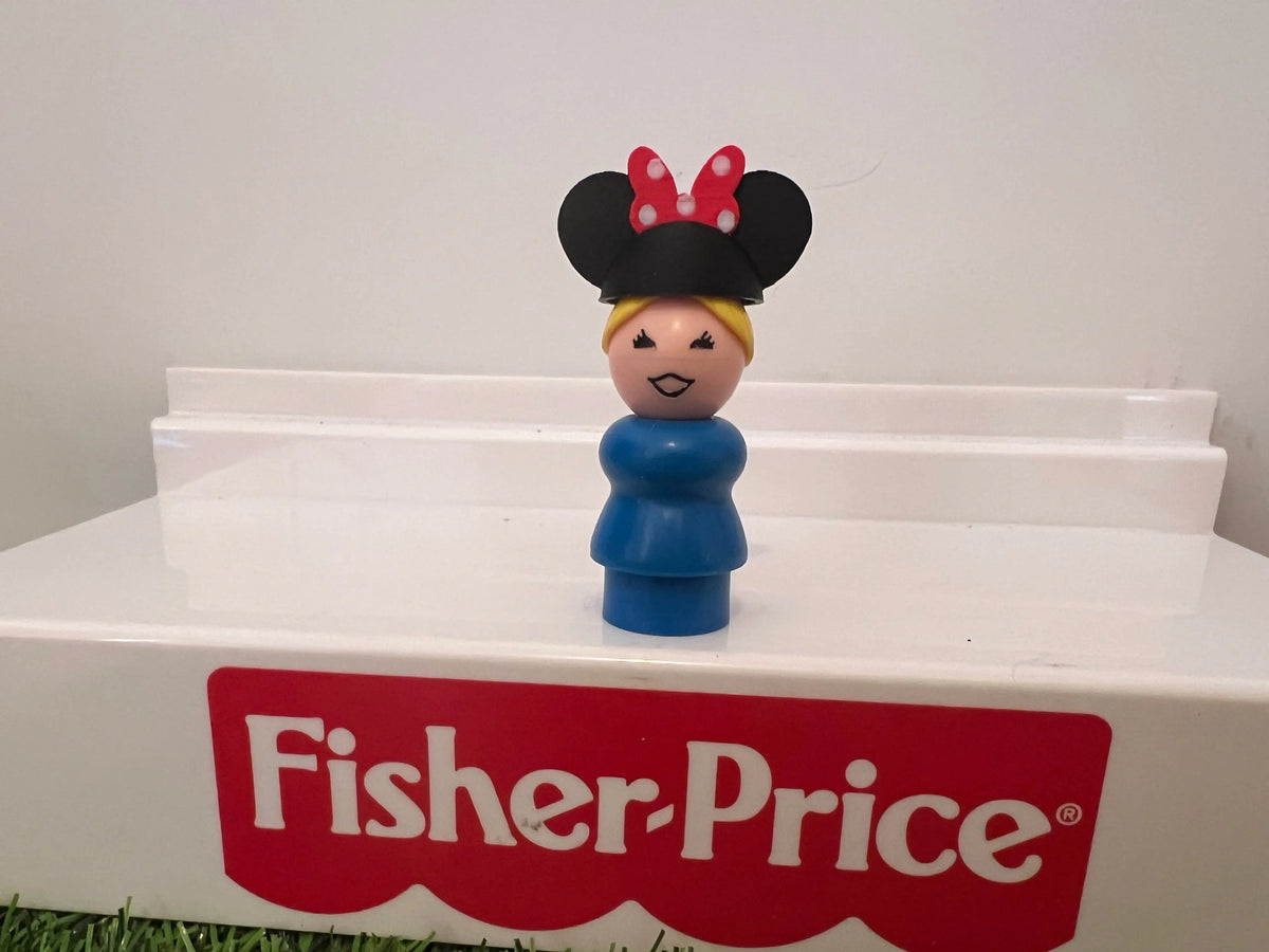 Minnie-style mouse ear hat on smiling figurine with blue outfit