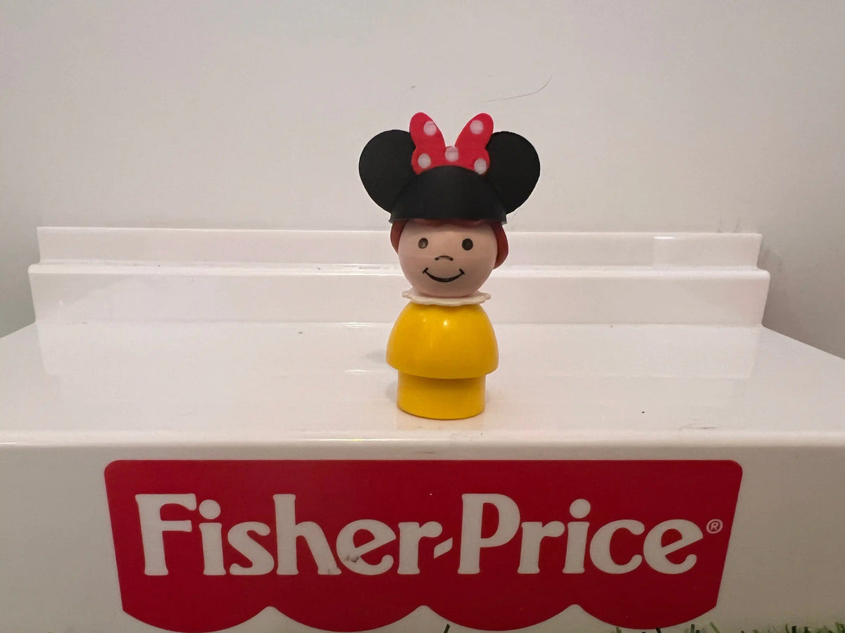 Minnie-style mouse ear hat on smiling figurine with yellow outfit