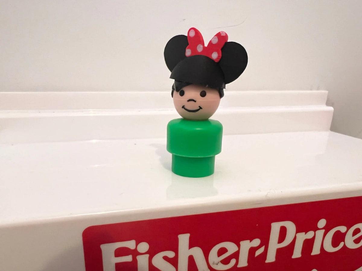 Minnie-style mouse ear hat on smiling figurine with green outfit