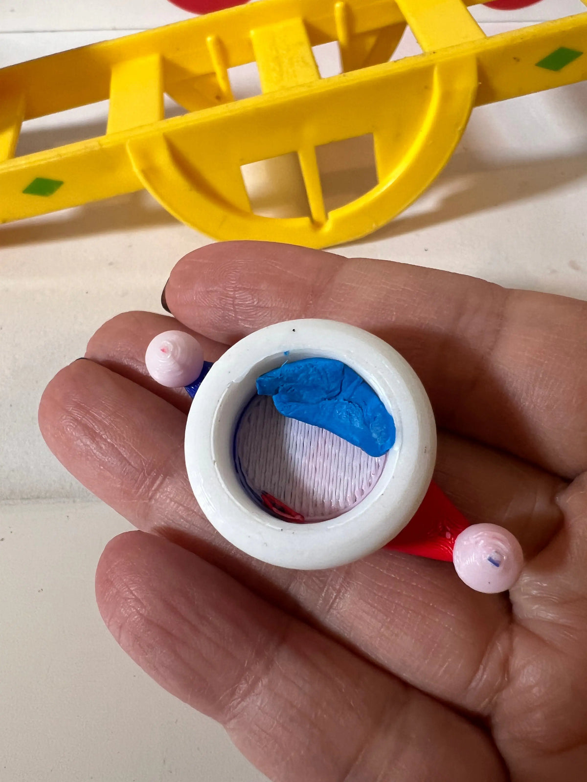Round white hat accessory insert with blue fabric detail, shown in a hand