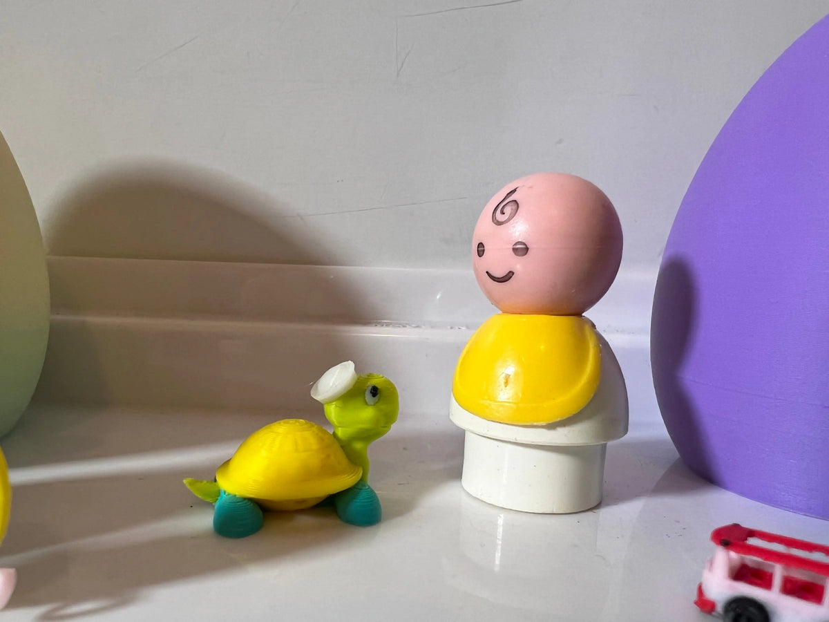 Yellow-and-white figurine with small green turtle and purple egg-shaped character