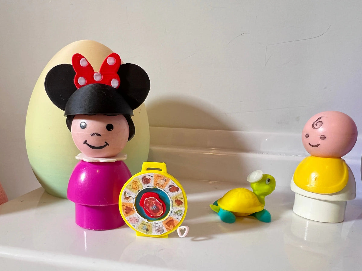 Miniature toy figurines with magenta figure, purple egg character, turtle, and spinning wheel