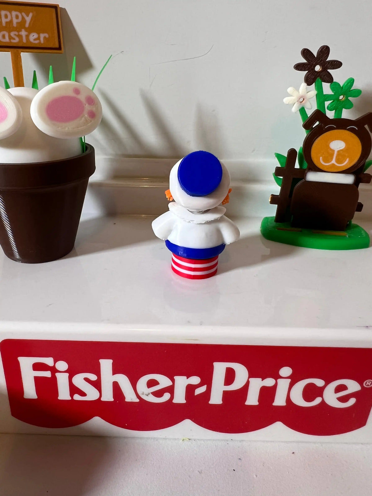 Raggedy Andy Easter doll figurine from behind with blue cap and striped dress