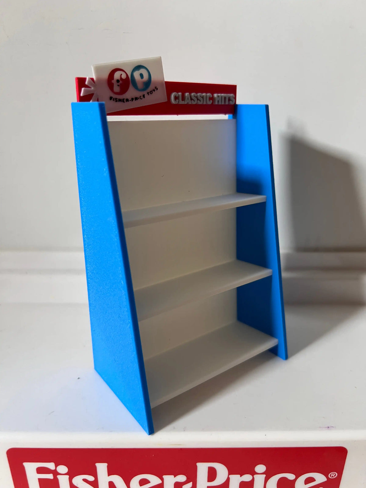 Angled Fisher-Price toy shelf, blue outer sides, white interior shelves