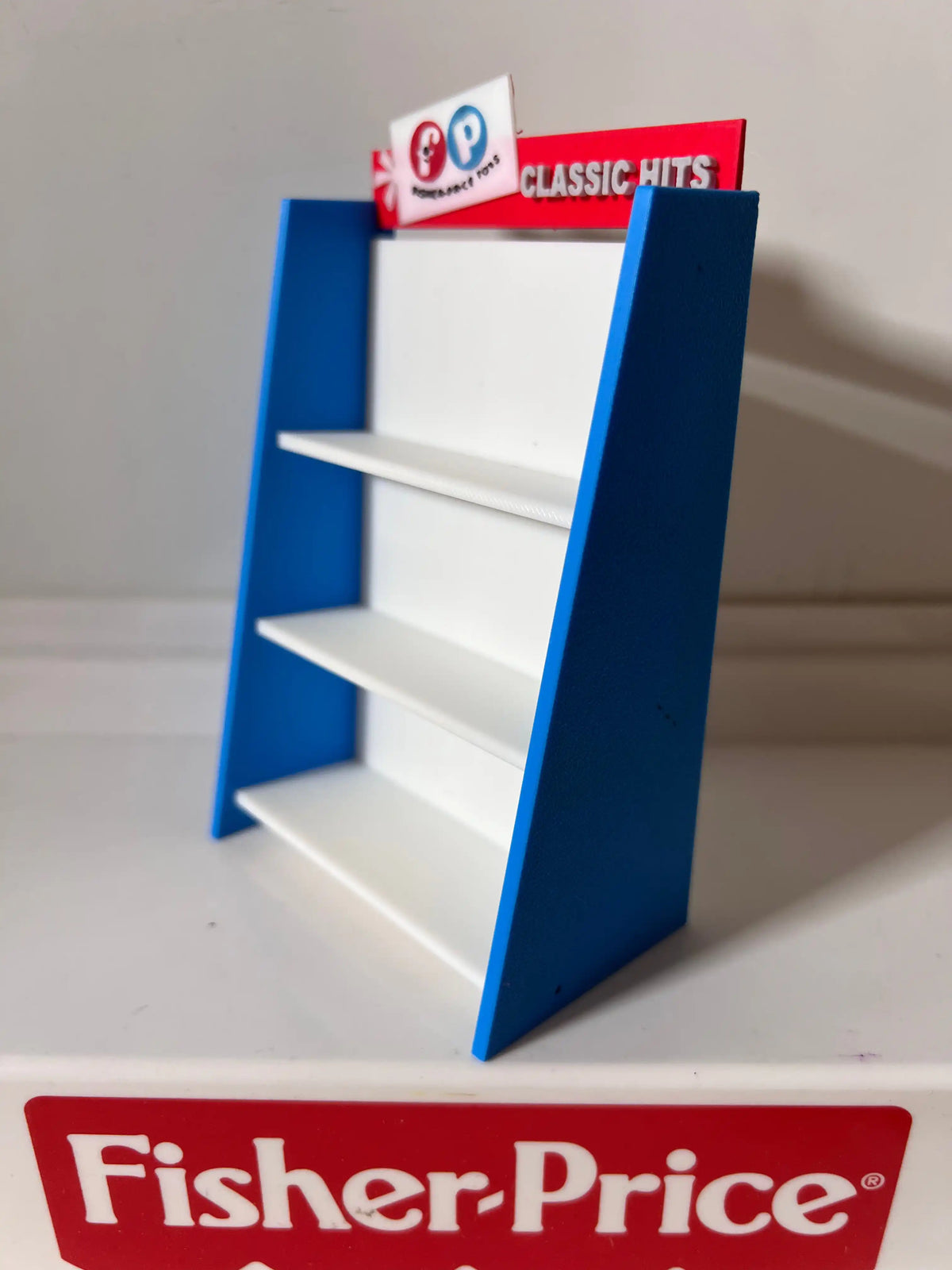 Fisher-Price toy shelf, blue frame and white shelves with boxed items on levels