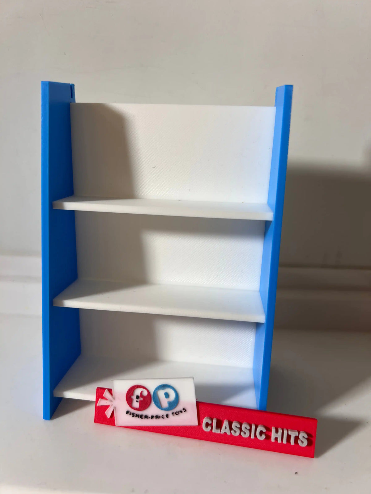 Blue and white Fisher-Price toy shelf with three empty levels and side panels