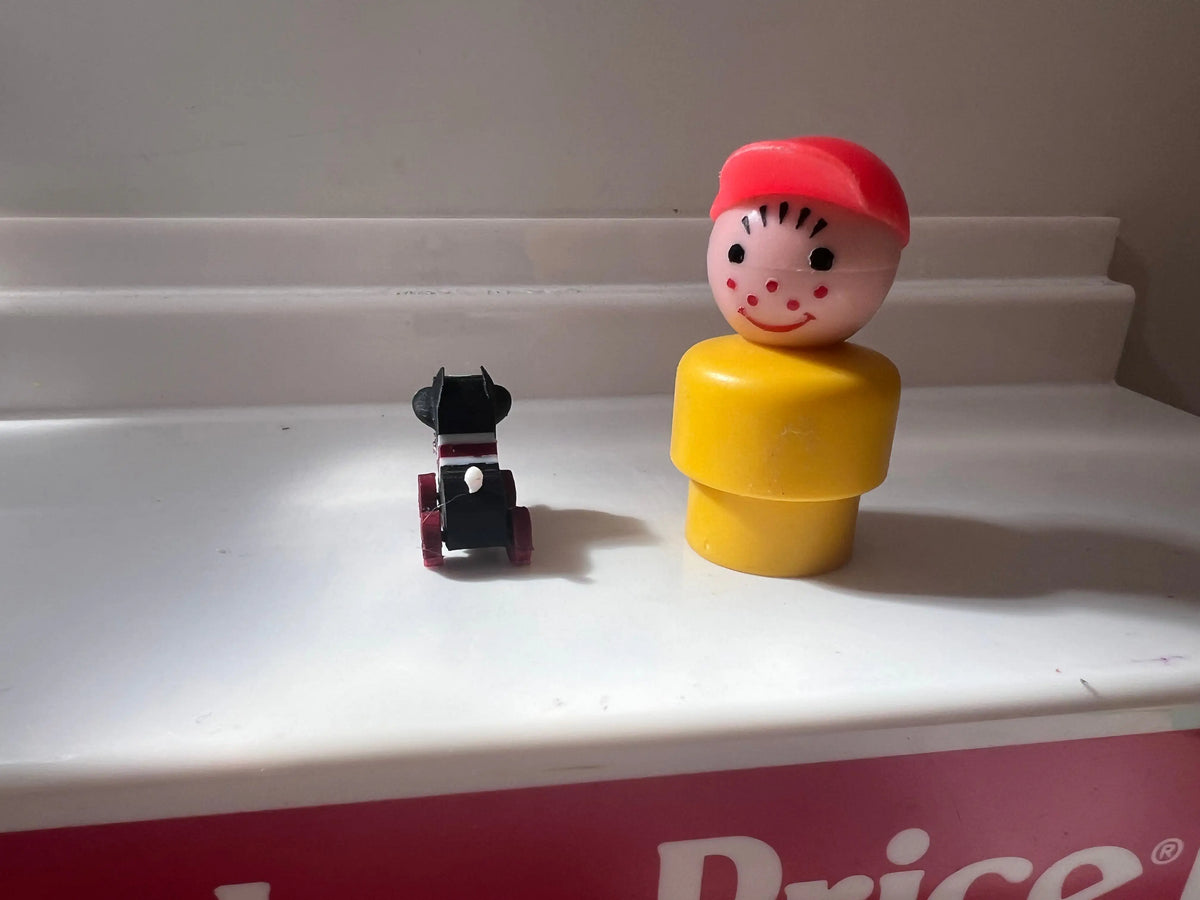 Mini child figure in yellow body with red cap, plus black dog toy on red box