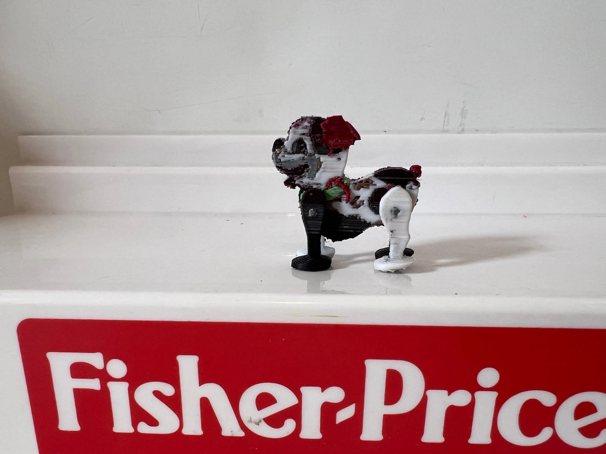 Miniature puppy figurine with red bow, facing left on a small white base