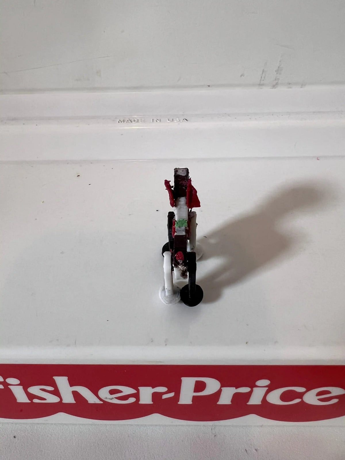 Miniature puppy figurine with red bow, rear view on a small white base