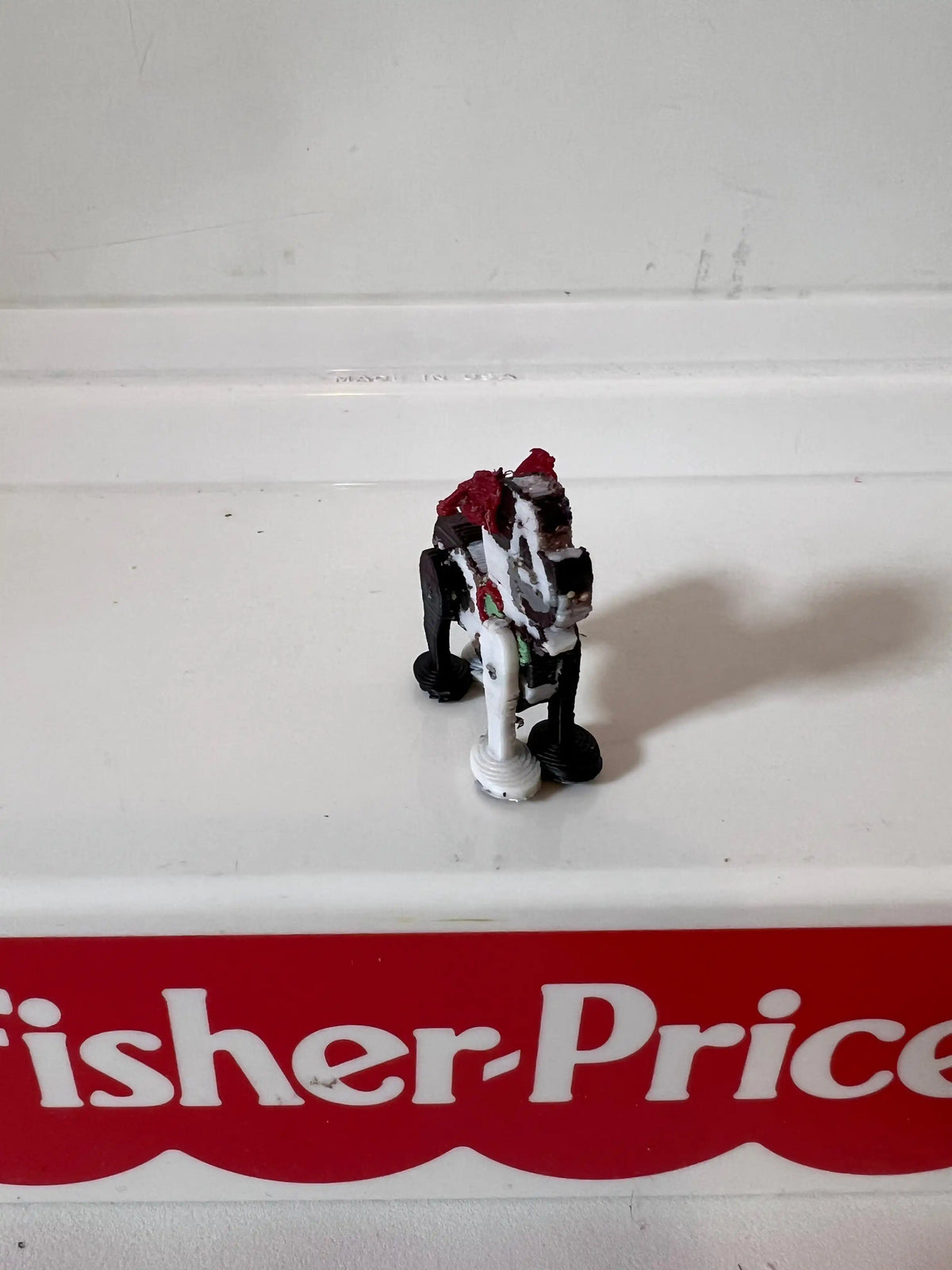 Miniature puppy figurine with red bow, side view with white legs and paws