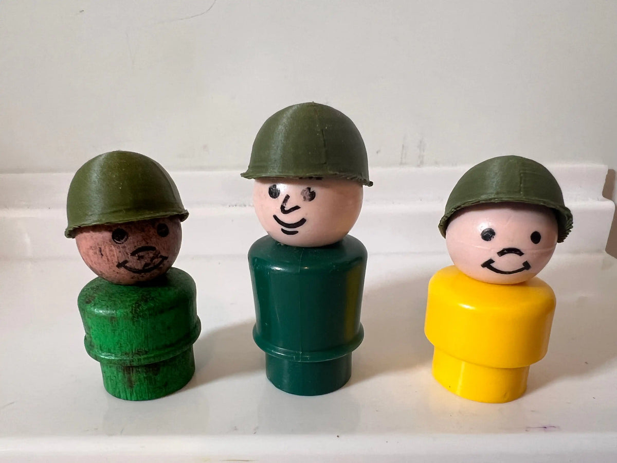 Three green army-style helmet figurines on a white toy display
