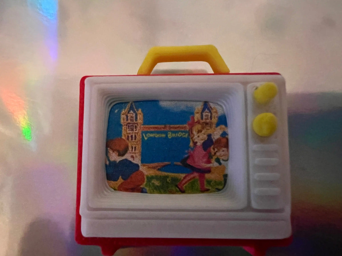 Miniature retro TV with red frame and yellow handle, blue screen with people scene