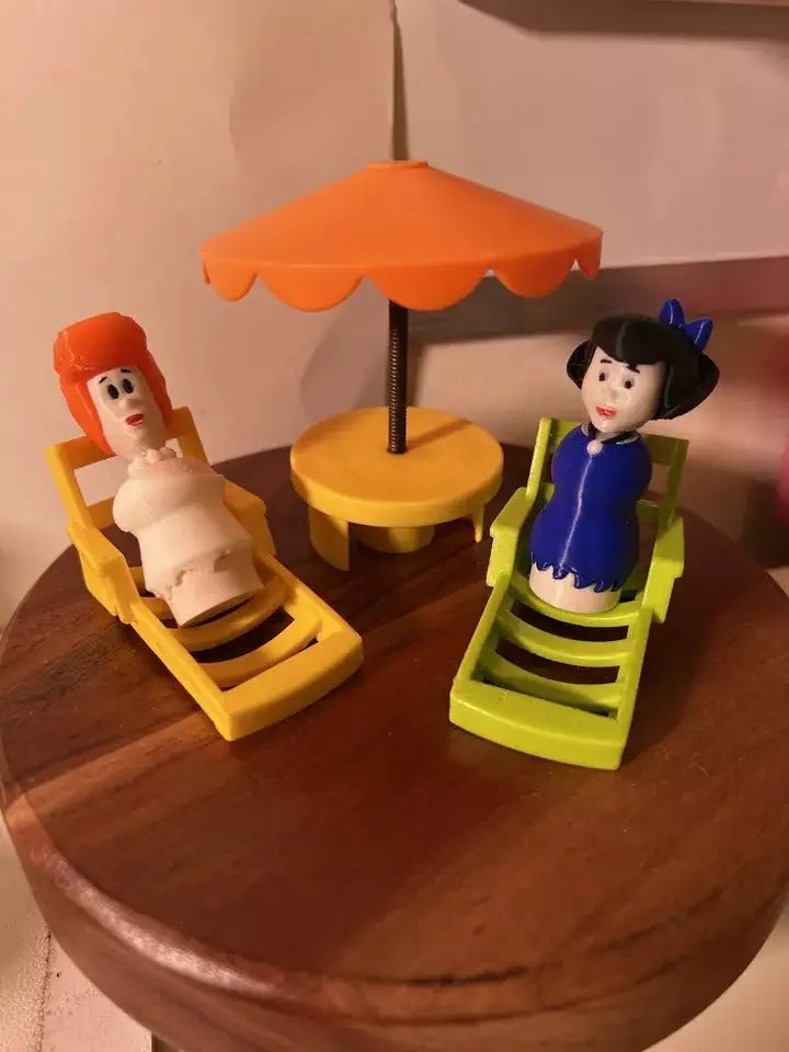 Custom 3D-printed Flintstones Betty Little People figure in a blue dress, relaxing in a lime green lounge chair.