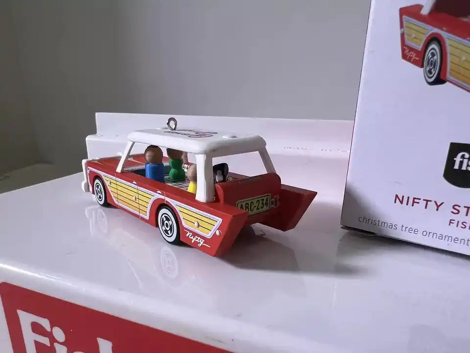 Red, yellow, and white station wagon ornament with two passenger figures and roof details