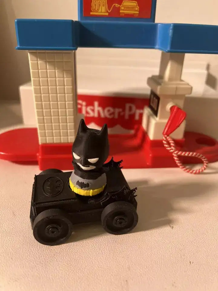 Batman mini figure in black suit with yellow belt, seated view