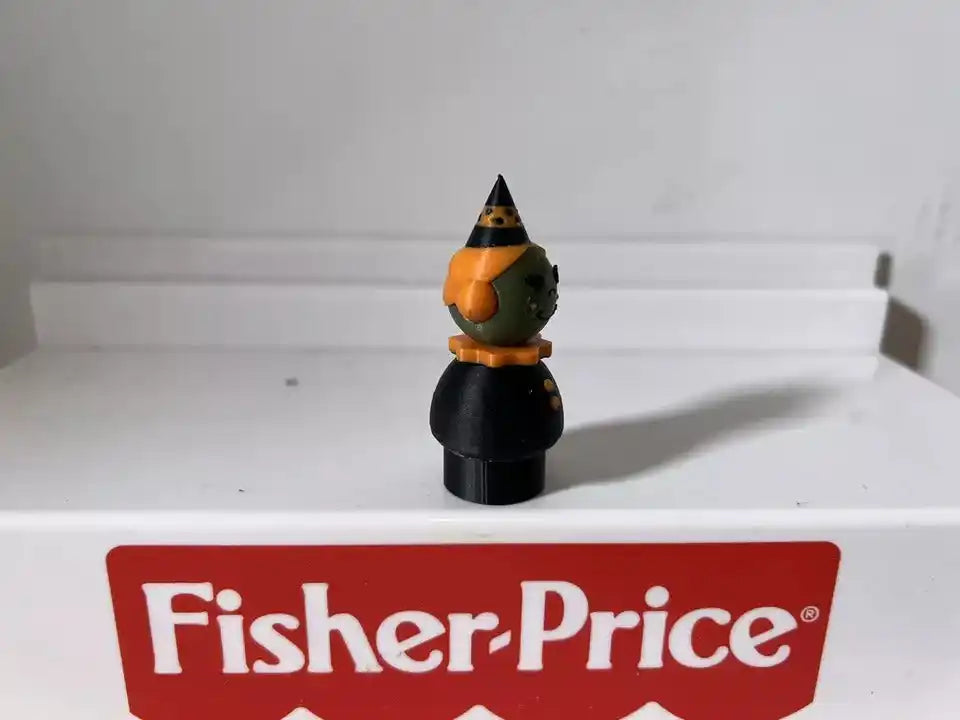 Green witch figurine in front view with orange hat and black outfit