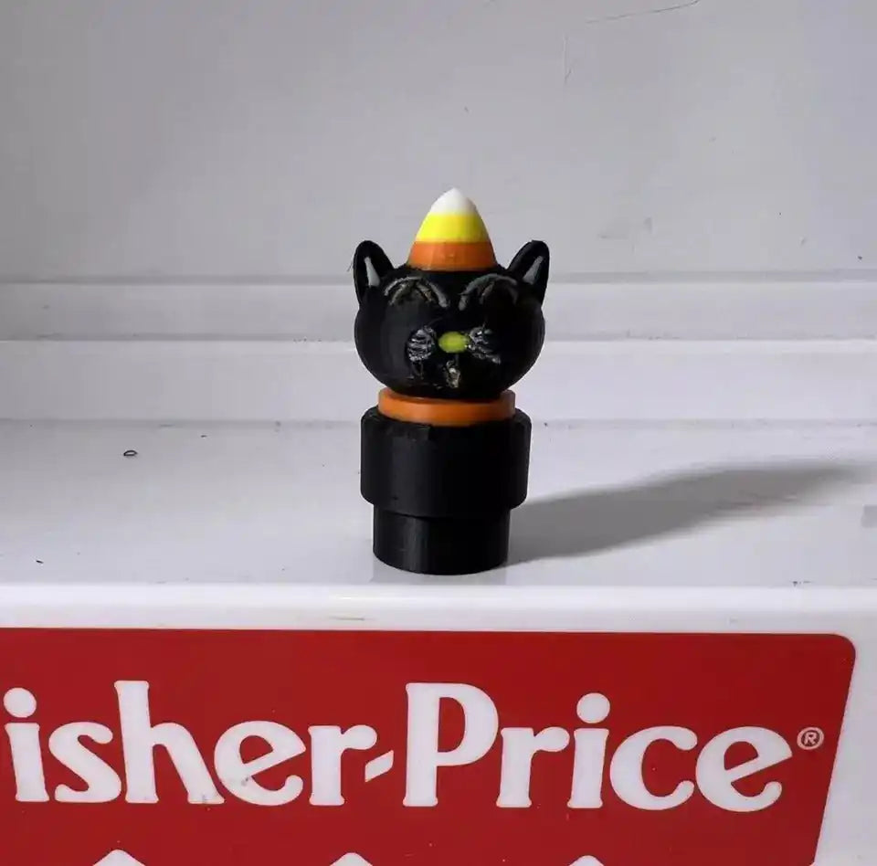 A custom 3D printed Halloween Spooky Little People figure, a black cat wearing a candy corn hat, on a Fisher-Price toy.