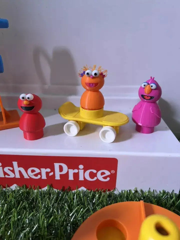 Three custom 3D-printed Little People-scale figures inspired by Sesame Street, including Telly, stand on a Fisher-Price surface.