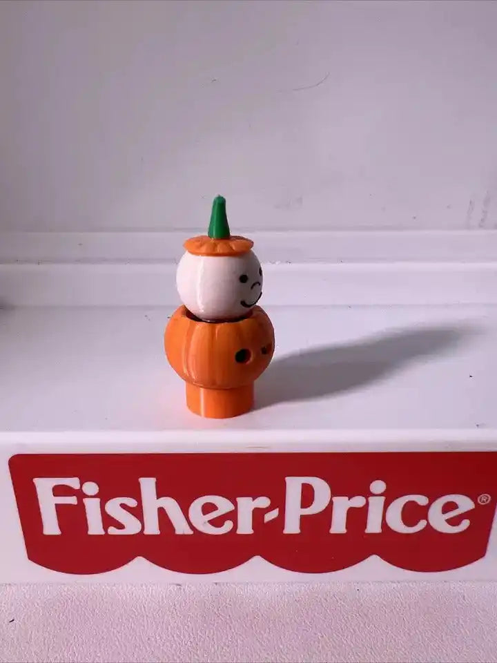 Orange pumpkin boy figurine with green-stem cap and white face