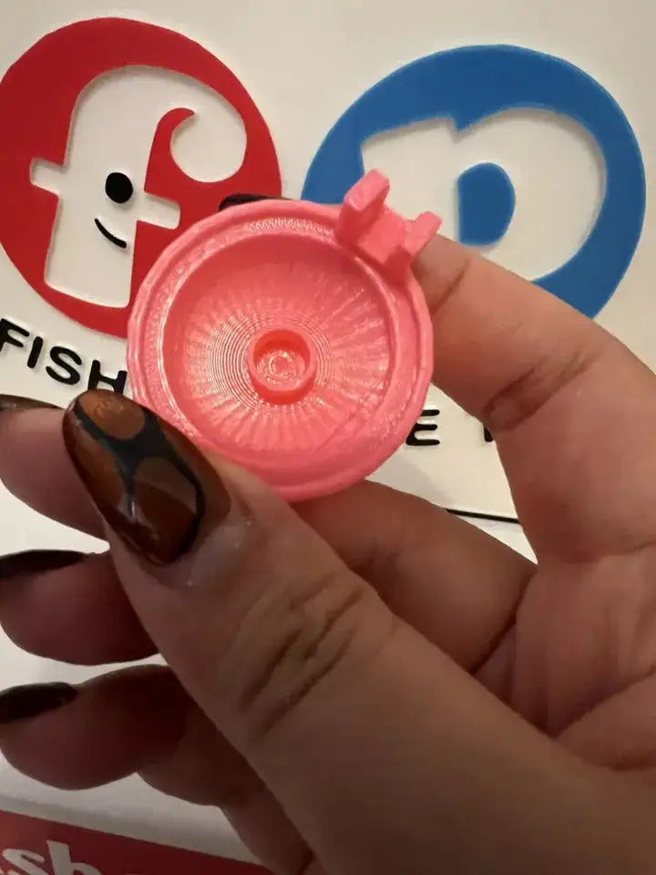 Pink replacement hair dryer nozzle cap with circular grille, held in hand
