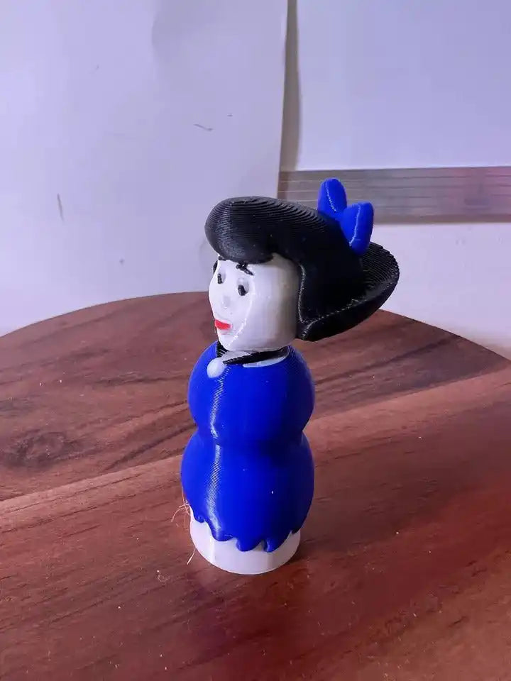 Betty doll figurine side view, blue dress and black bonnet with blue bow