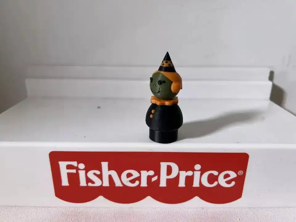 Halloween witch figurine with black dress and hat, green face and orange collar detail.